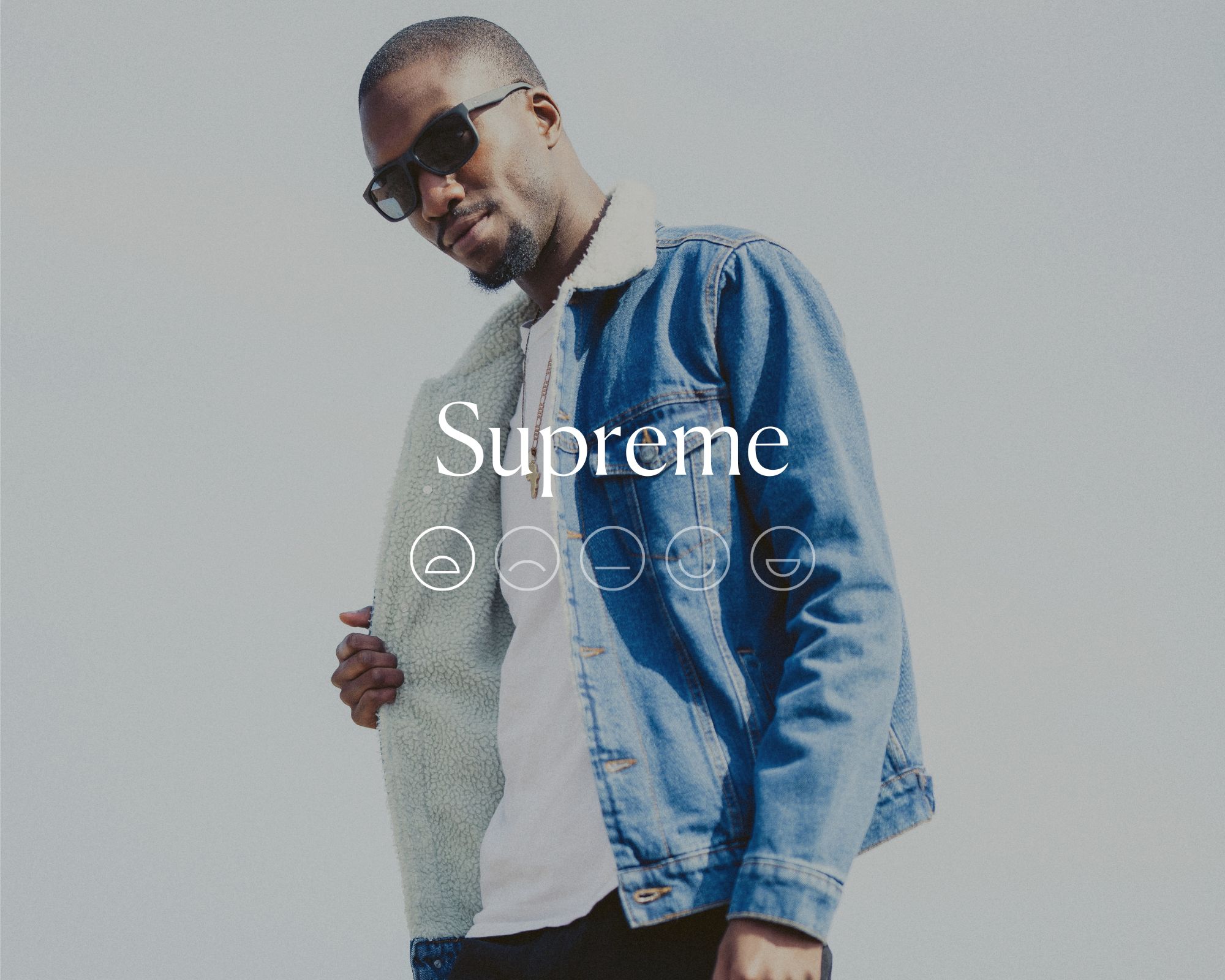 A man in sunglasses and a denim jacket with the word Supreme and a sad emoji face overlaid in white text.