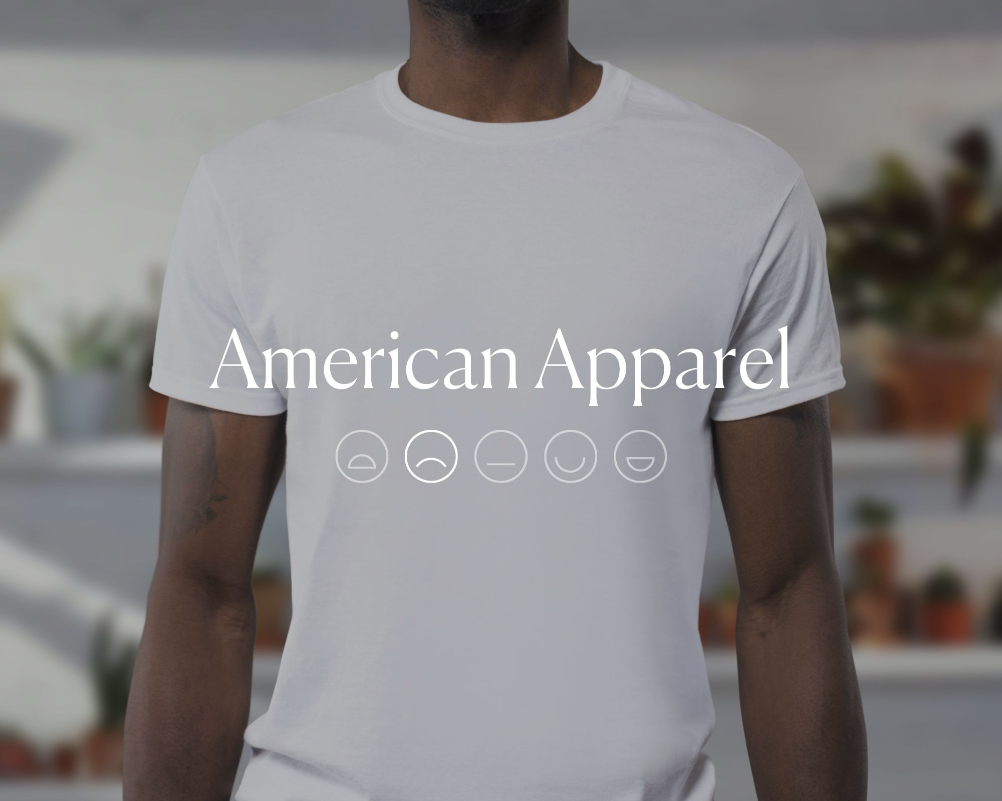 Someone wearing a white t-shirt with the words American Apparel and a sad emoji face overlaid in white text.