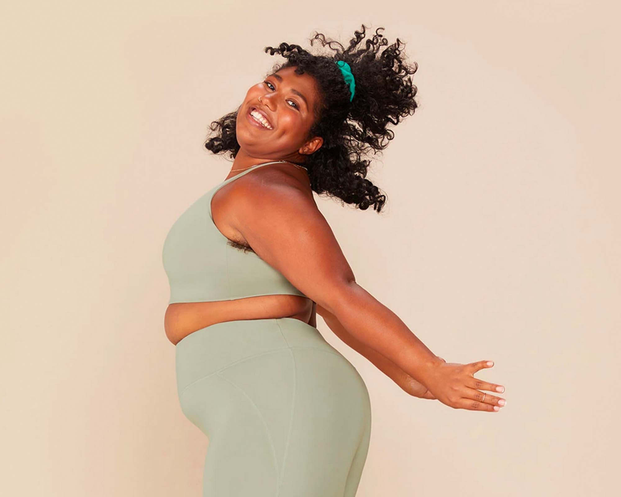 plus size woman of colour happy in light green recycled plastic yoga wear