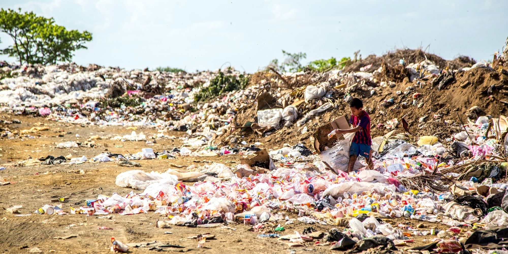 boy standing in pile of plastic waste