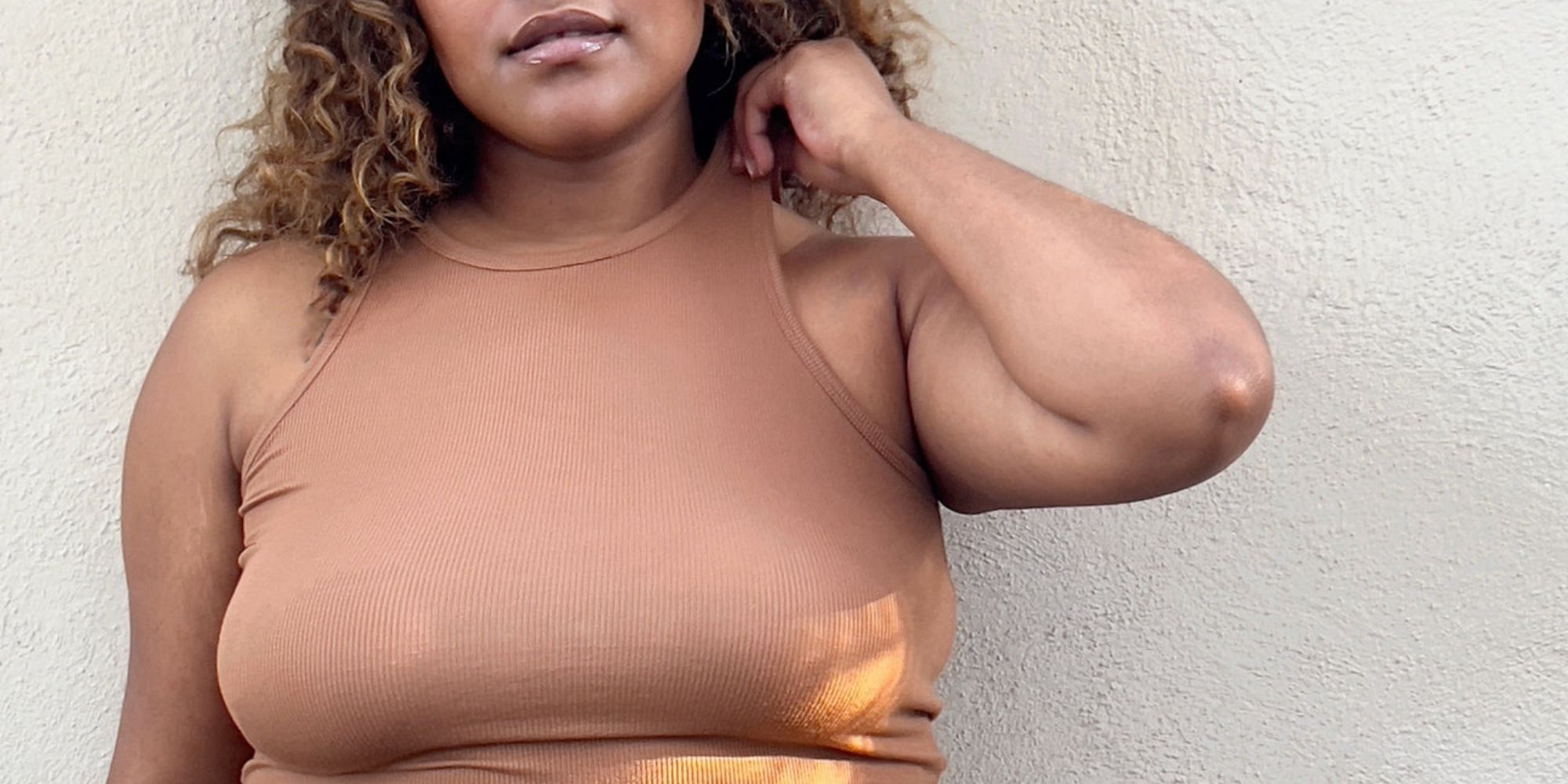 Cropped shot of someone's chest, they are wearing a ribbed tank top by Proclaim that matches their medium skintone.
