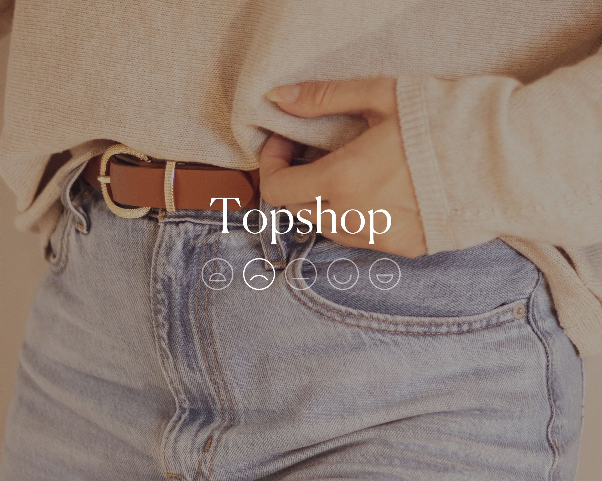 Close up of a sweater and jeans overlaid with white text reading Topshop and a sad emoji face highlighted.