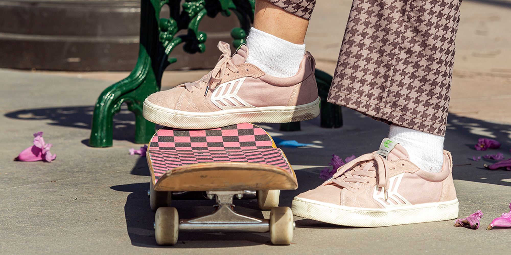 person wearing pink ethically made skate shoes on pink and black skateboard