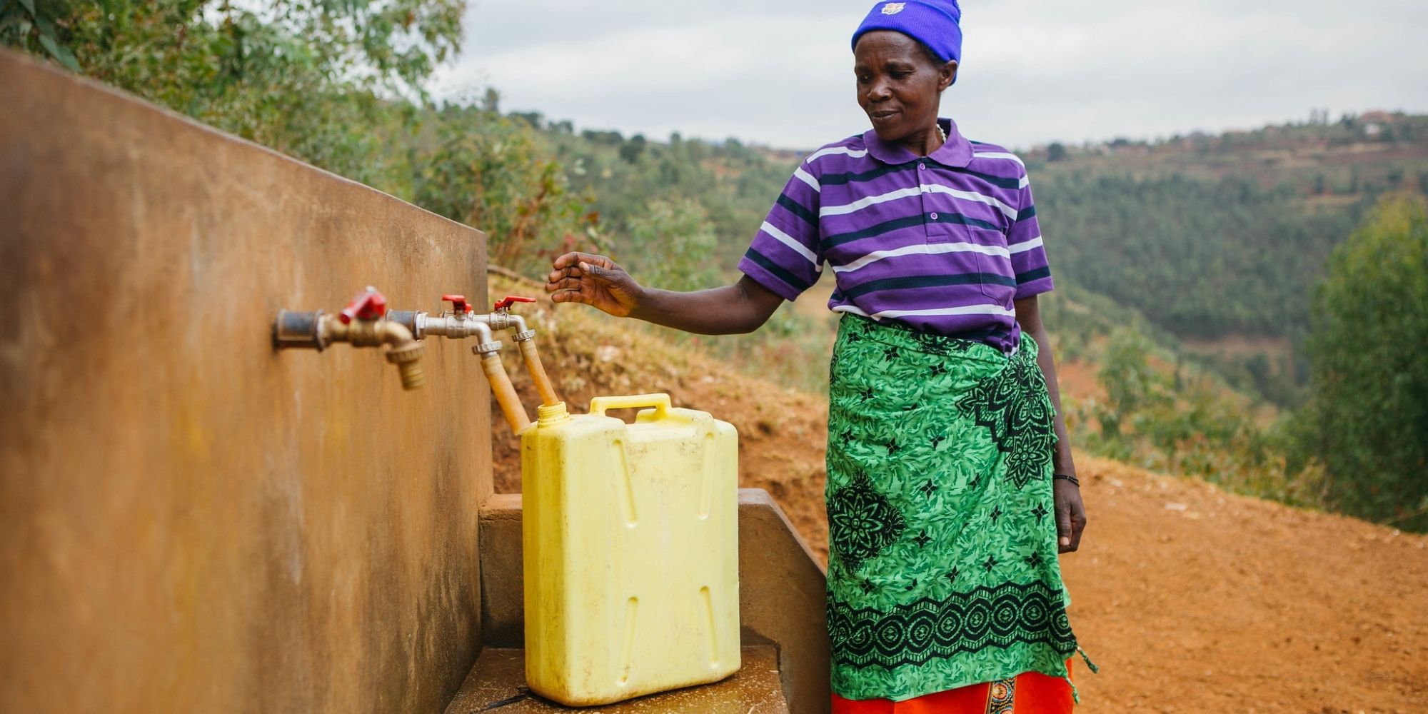 woman in Africa filling yellow water bucket thanks to Water For People charity