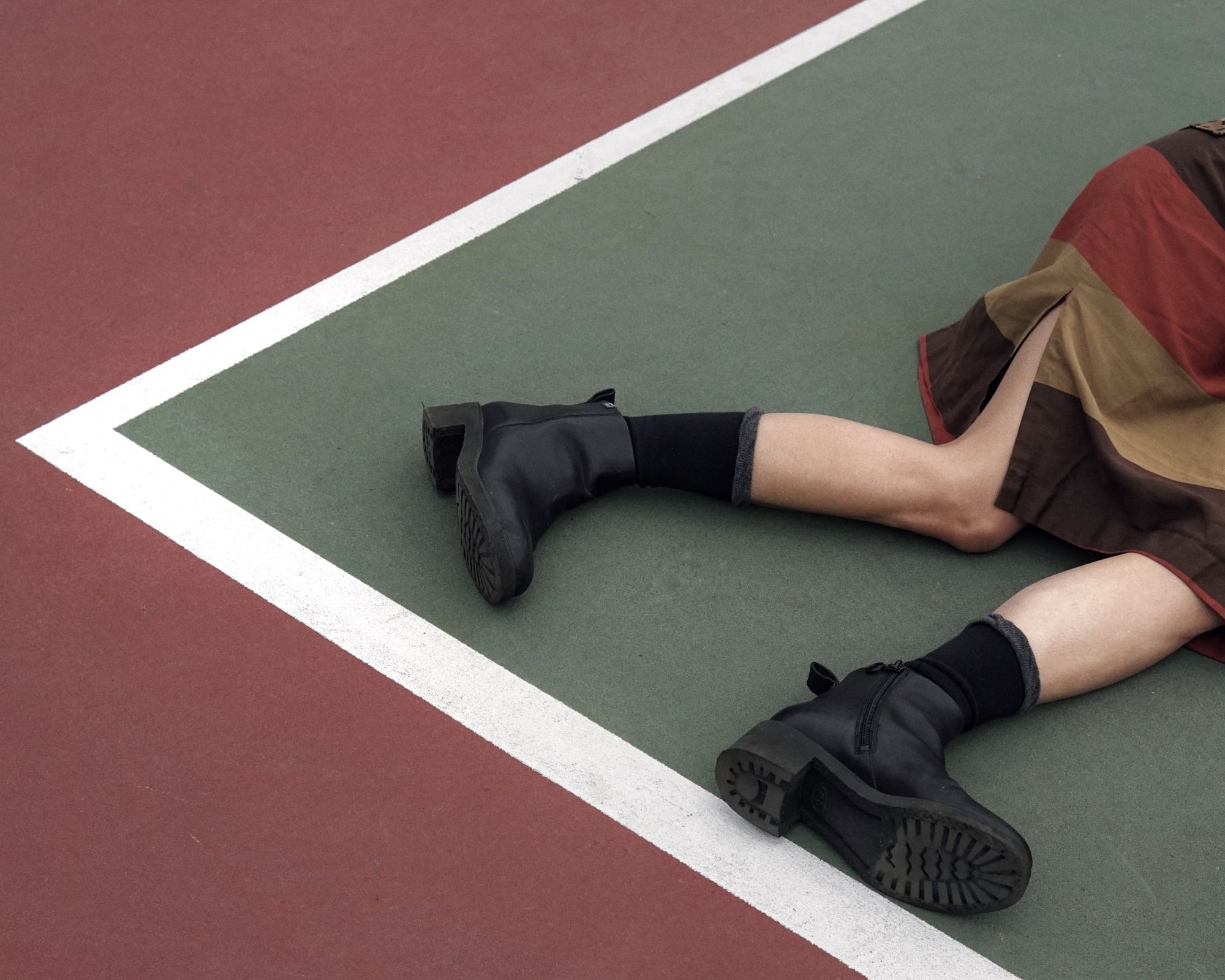 Someone laying on a ball court wearing heavy black boots.