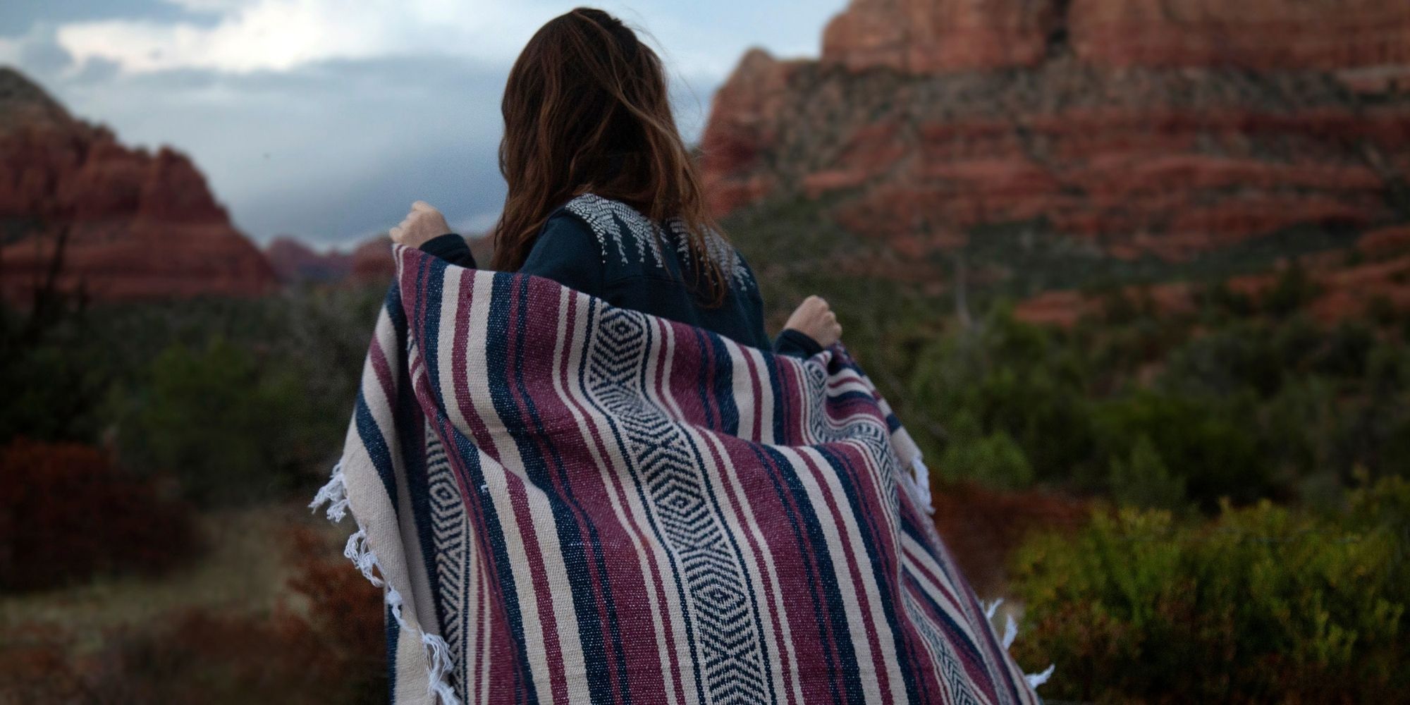 woman looking over valley wearing sustainable blanket by Happy Earth
