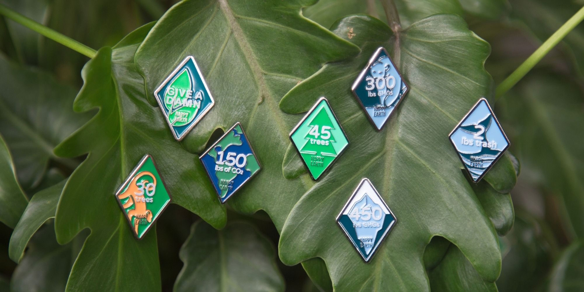 seven sustainability-focused pins on a leaf by Happy Earth