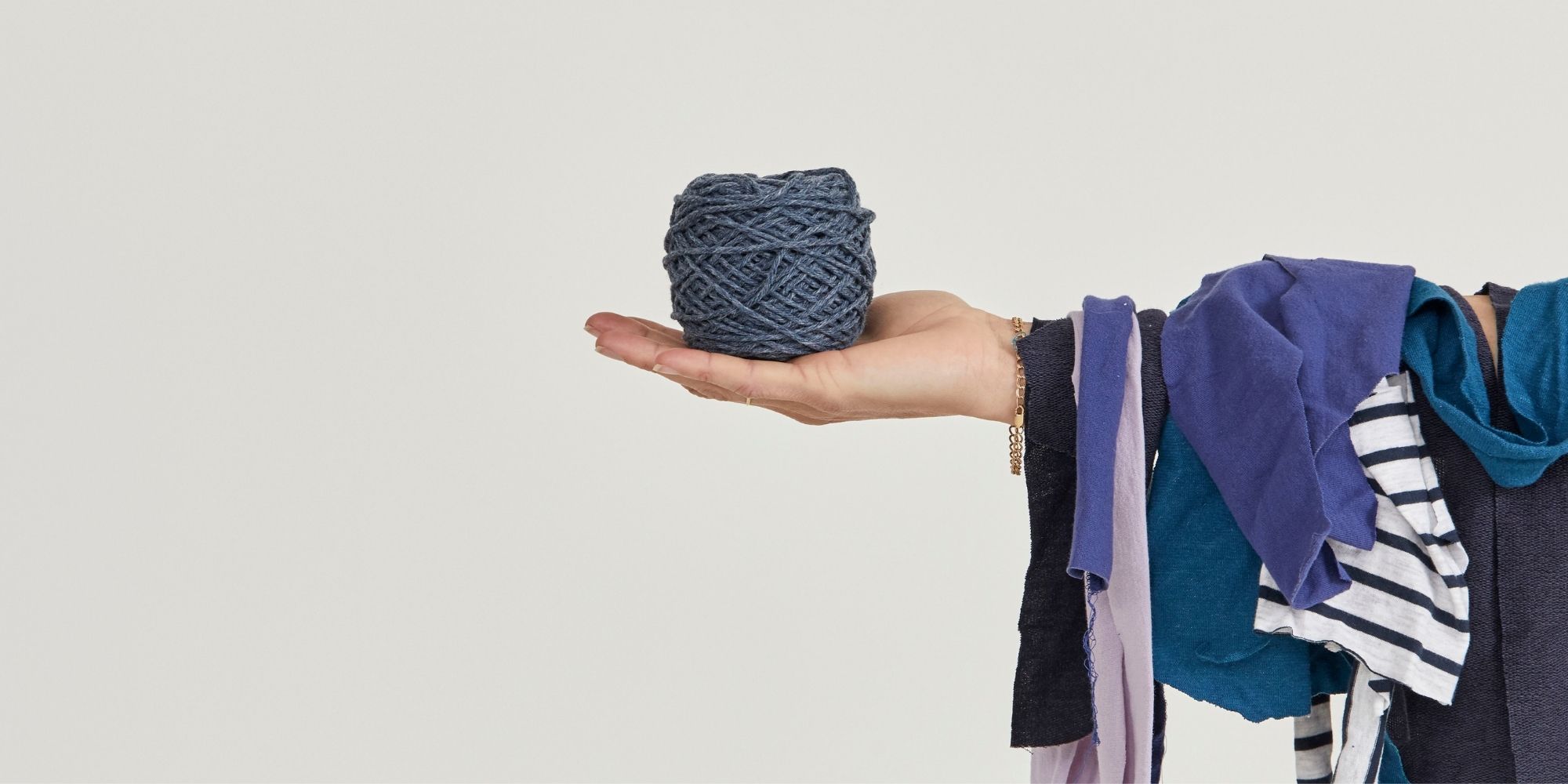 person holding up scraps of offcut fabric and ball of zero waste yarn from Citizen Wolf