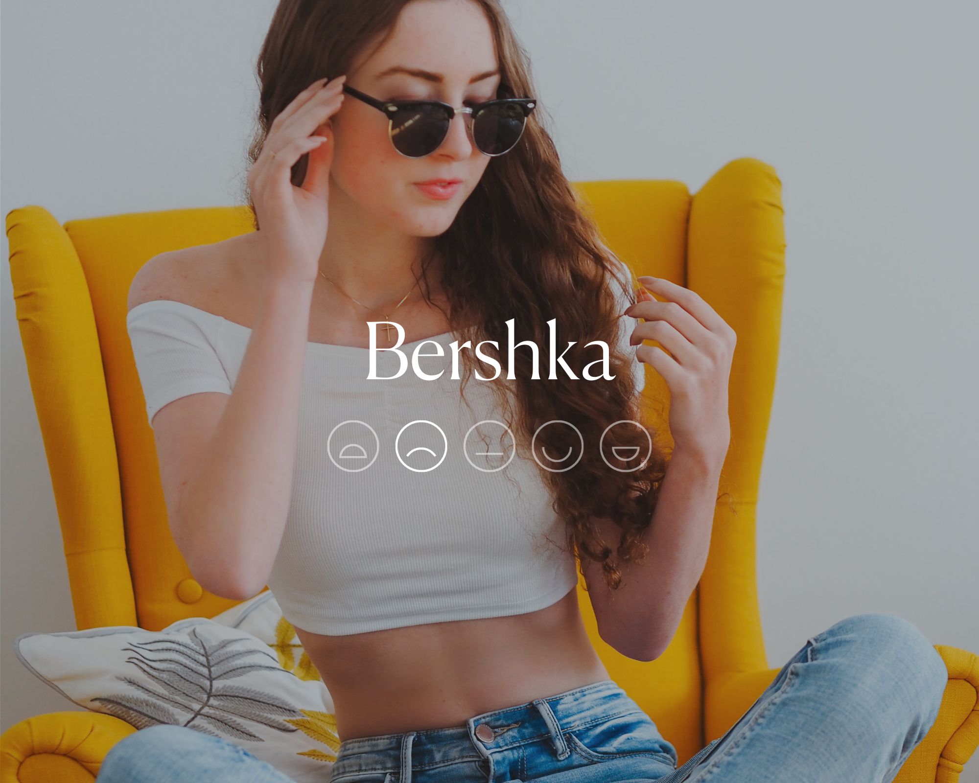 Someone sitting in a yellow chair wearing sunglasses, a white crop top, and jeans. The word
