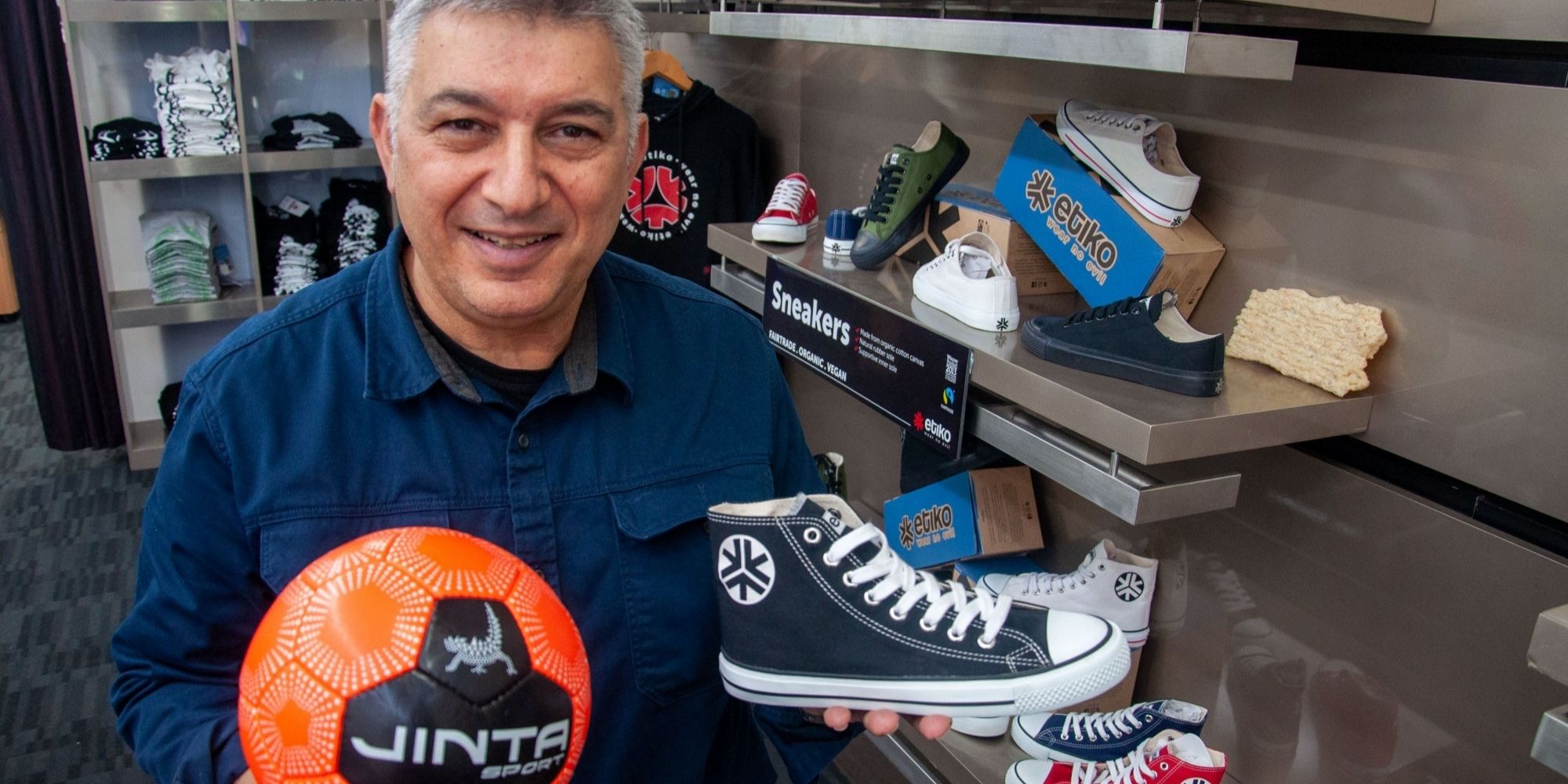 Etiko founder Nick holding up sustainably made sports ball and sneaker