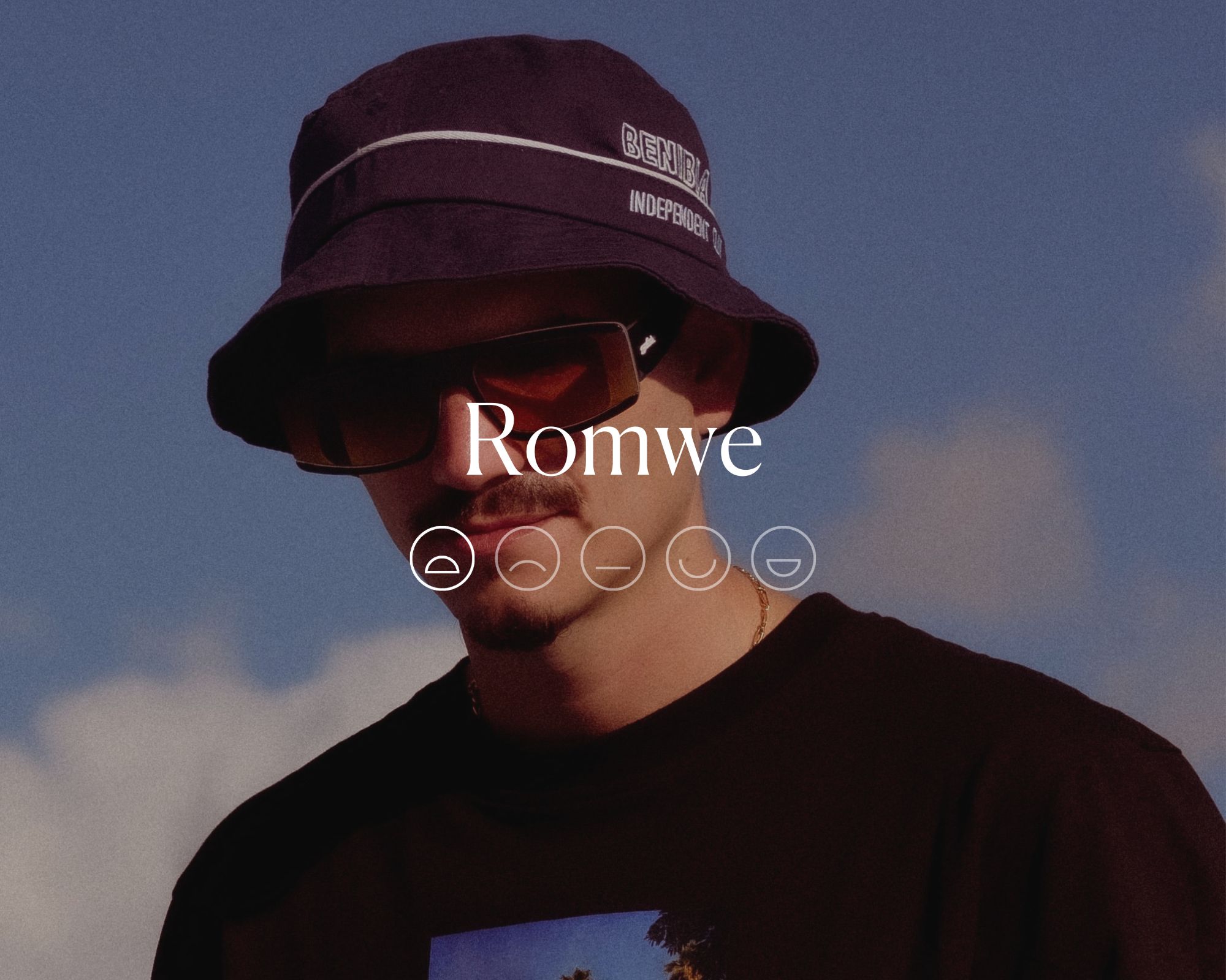A man wearing sunglasses, a printed shirt, and a bucket hat in an image faded behind the word Romwe with a highlighted sad face.