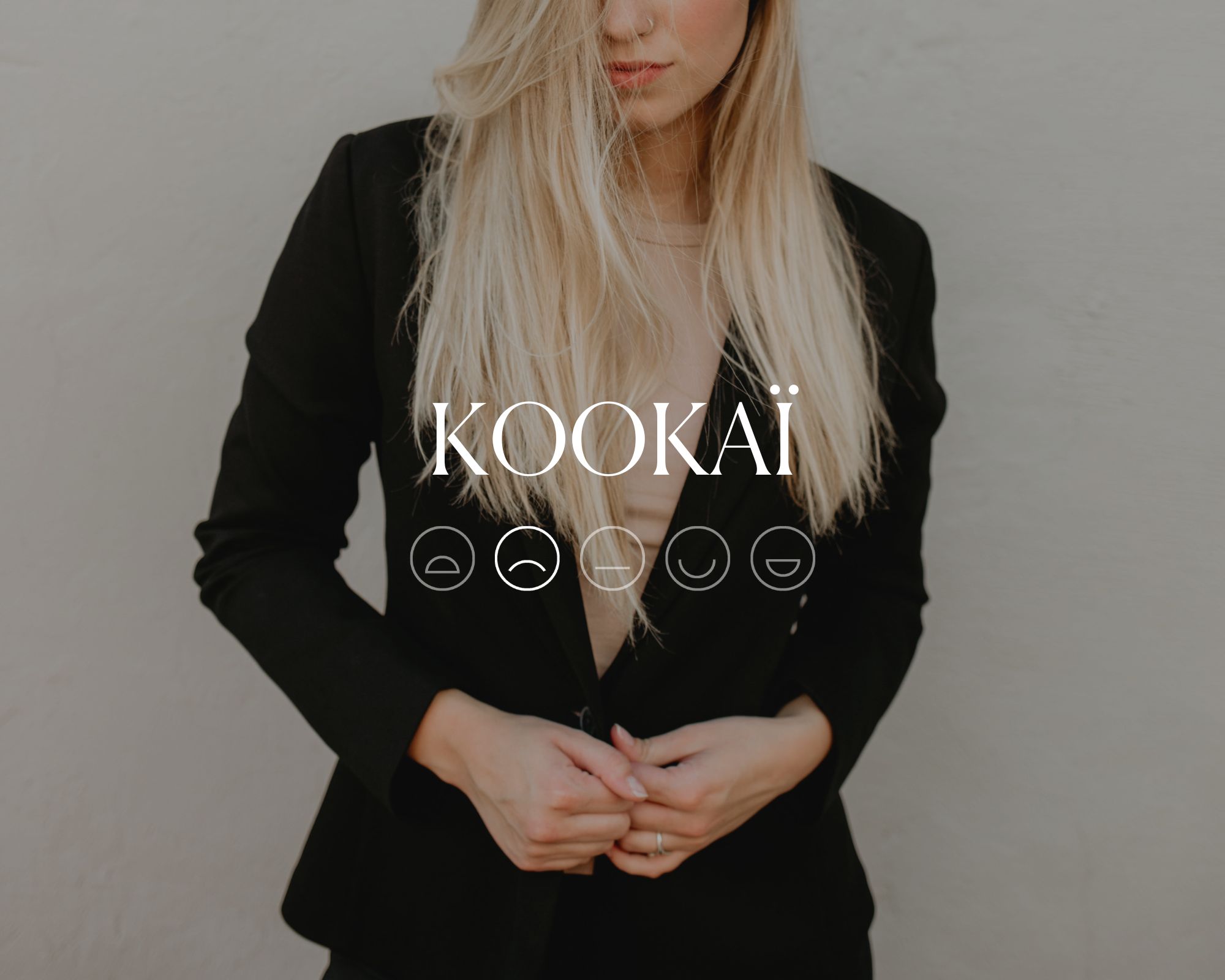 Someone wearing a sleek black blazer with the word KOOKAI and a sad emoji face overlaid in white text.