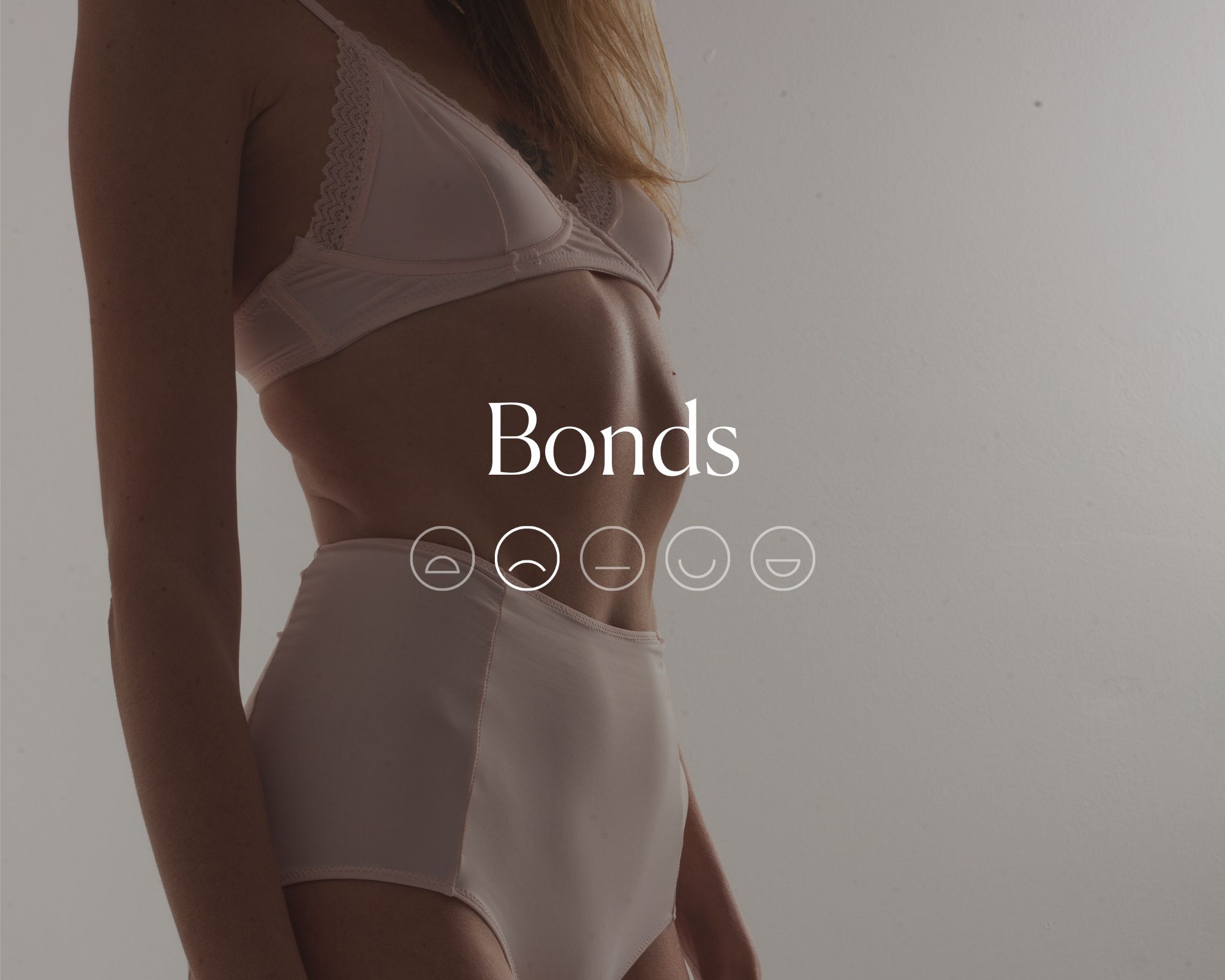 Someone wearing a white lingerie set overlaid by white font saying Bonds with a highlighted sad face emoji.