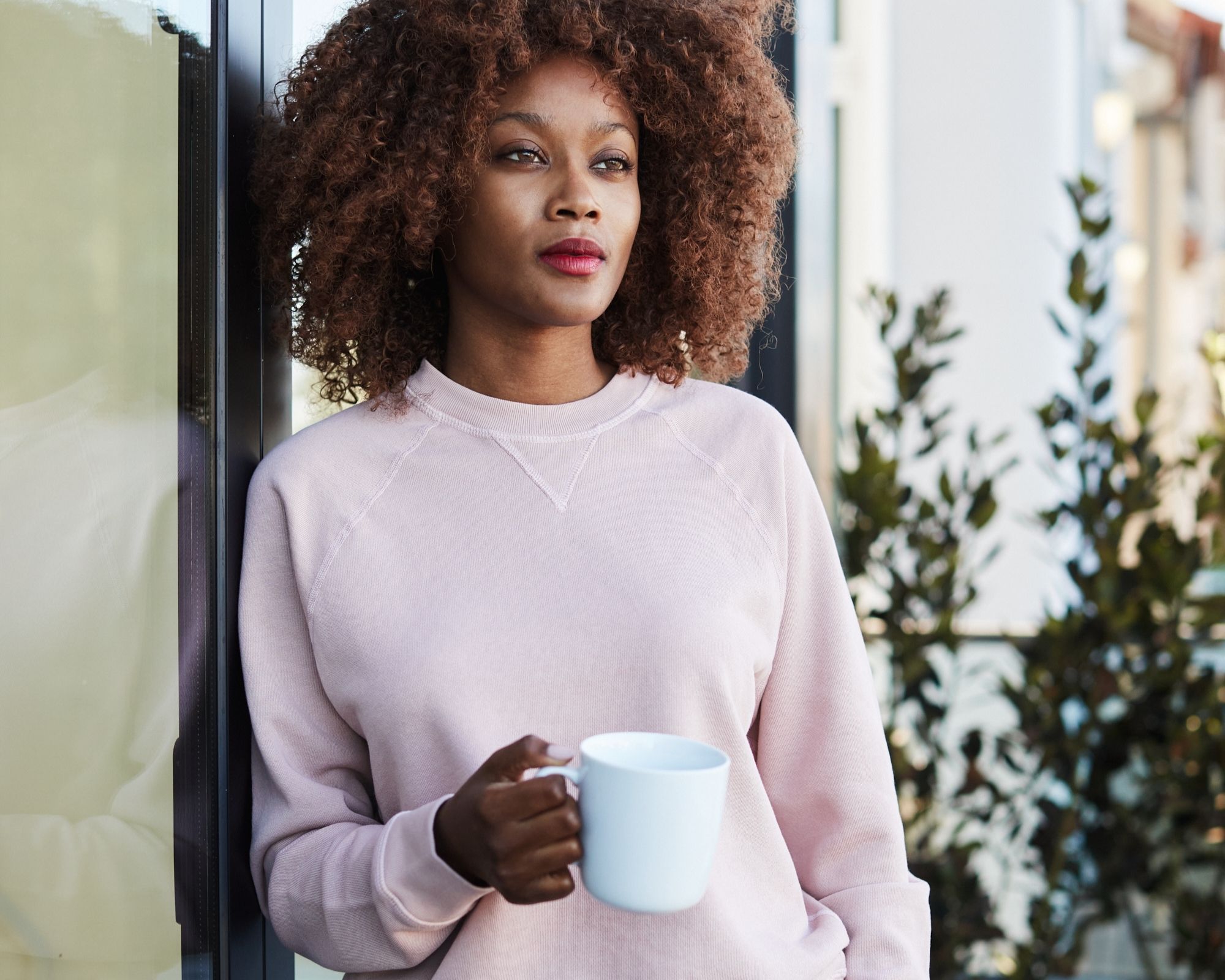 Person holding tea and wearing a pink sustainable sweatshirt designed by The Classic T-Shirt Company.
