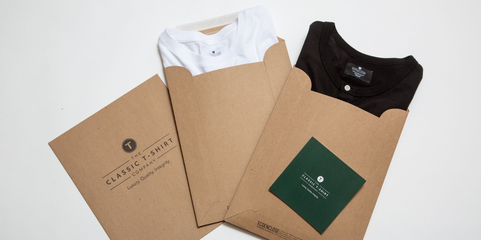 The Classic T-Shirt Company eco-friendly packaging laid out in a row with black and white tees poking out.