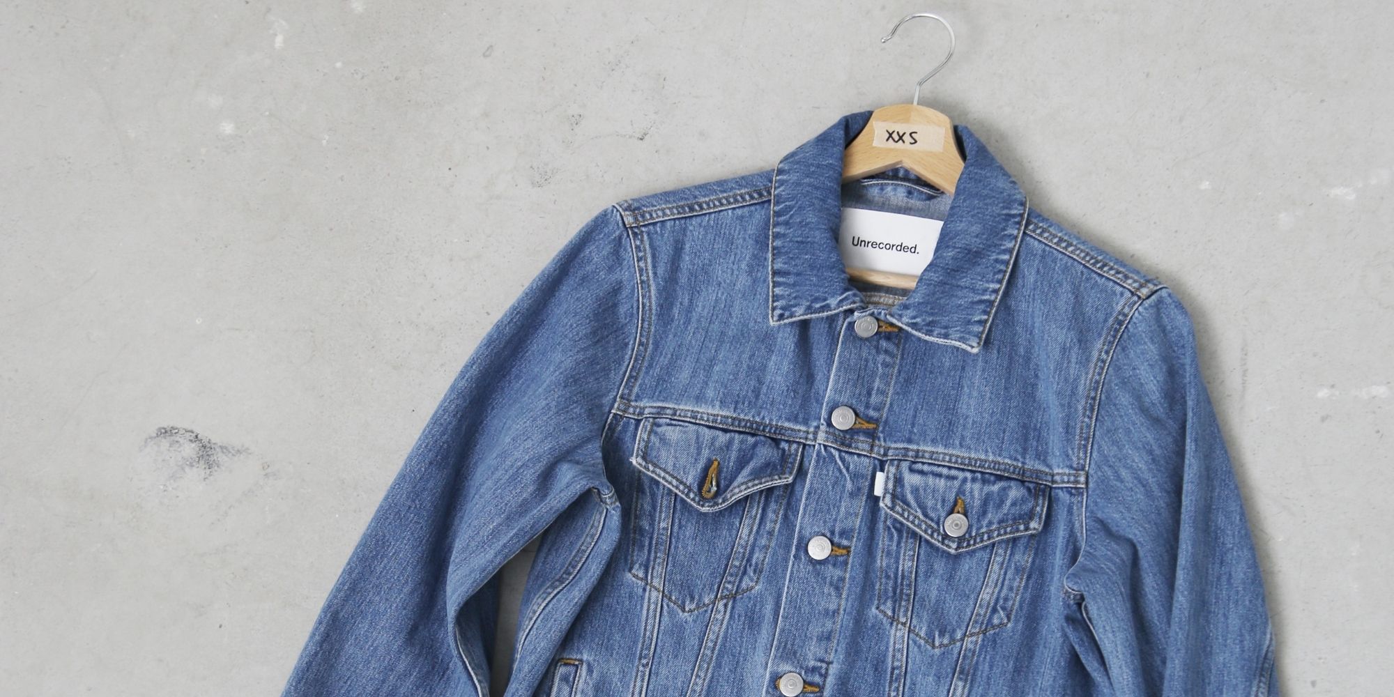 Cropped shot of a sustainable denim jacket flat on the ground, made by Unrecorded.