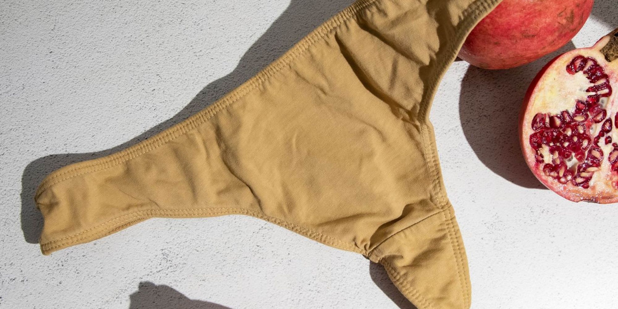 Close up of a pair of naturally dyed underwear next to pomegranates, designed by KENT.