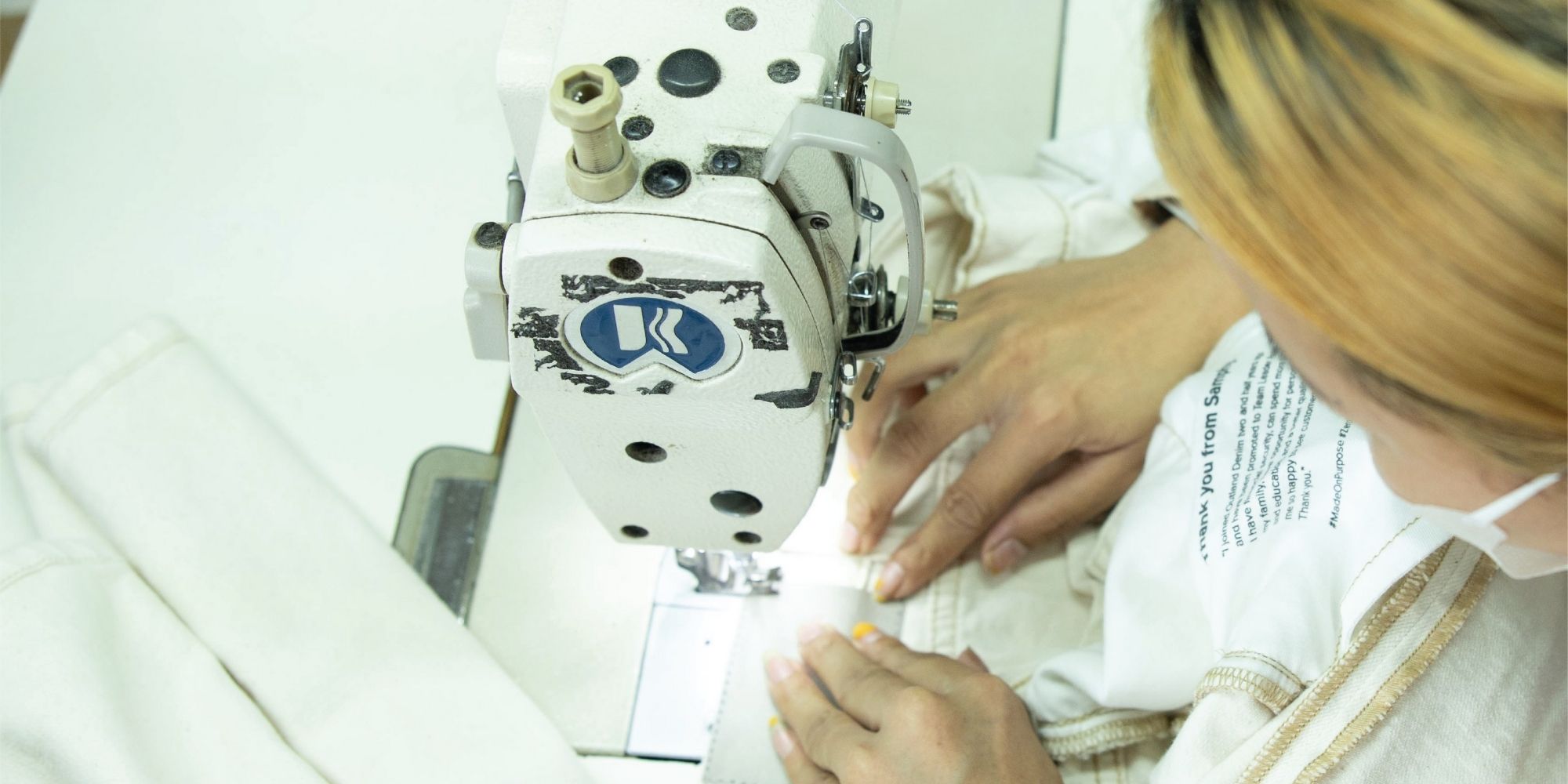 Close up of an Outland Denim worker stitching a pair of jeans.