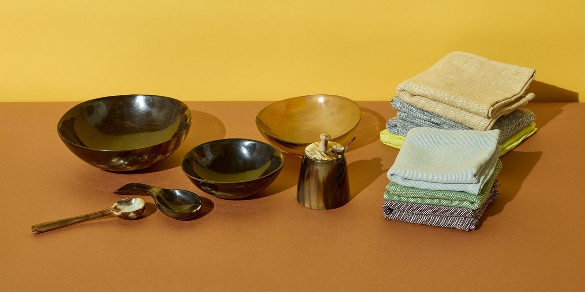 A table spread of upcycled horn dishes and handwoven tea towels by Raven + Lily.