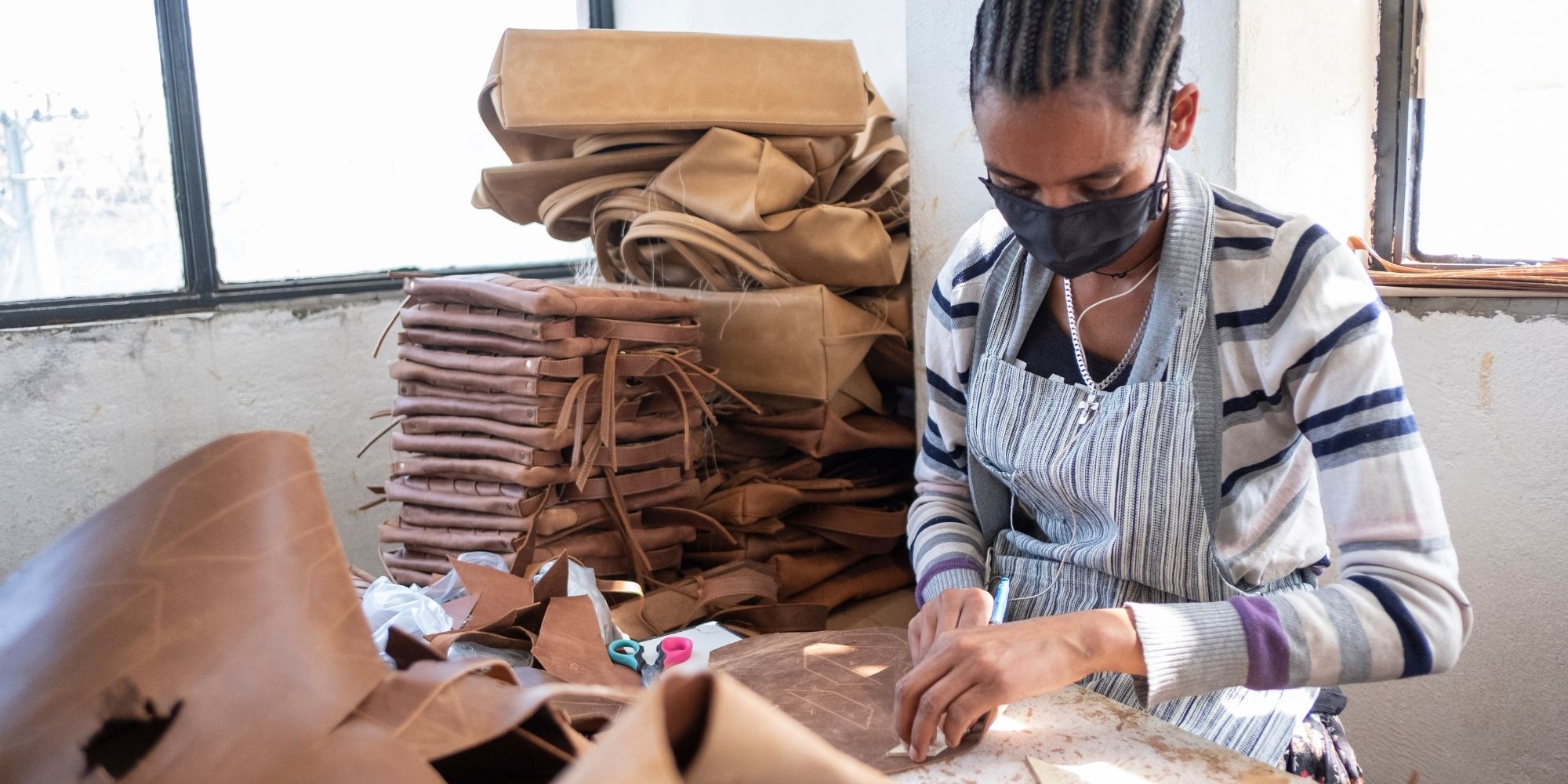 An artisan working on leathergoods for Raven + Lily.