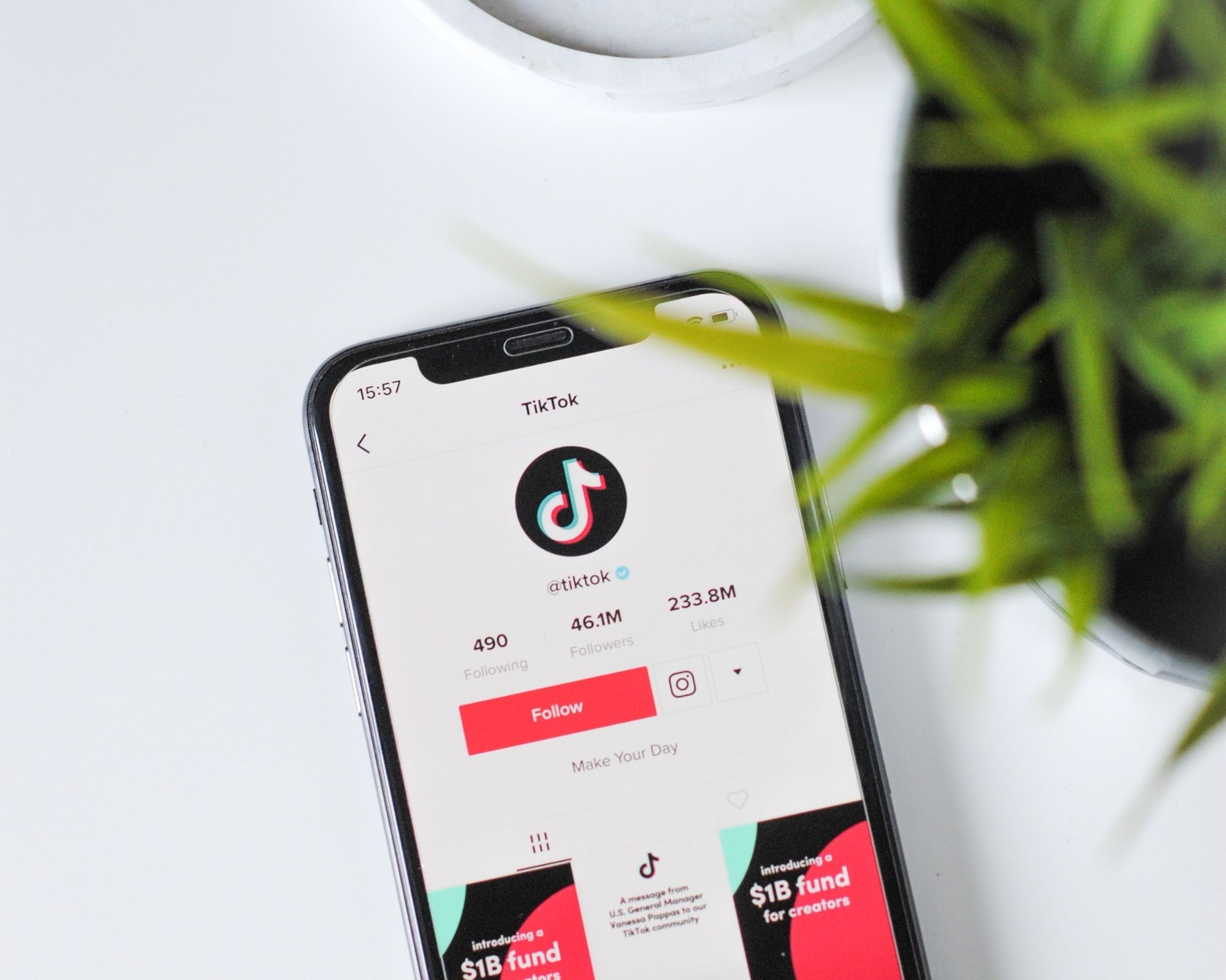 A phone on a desk with a plant and coaster, featuring TikTok on the screen.