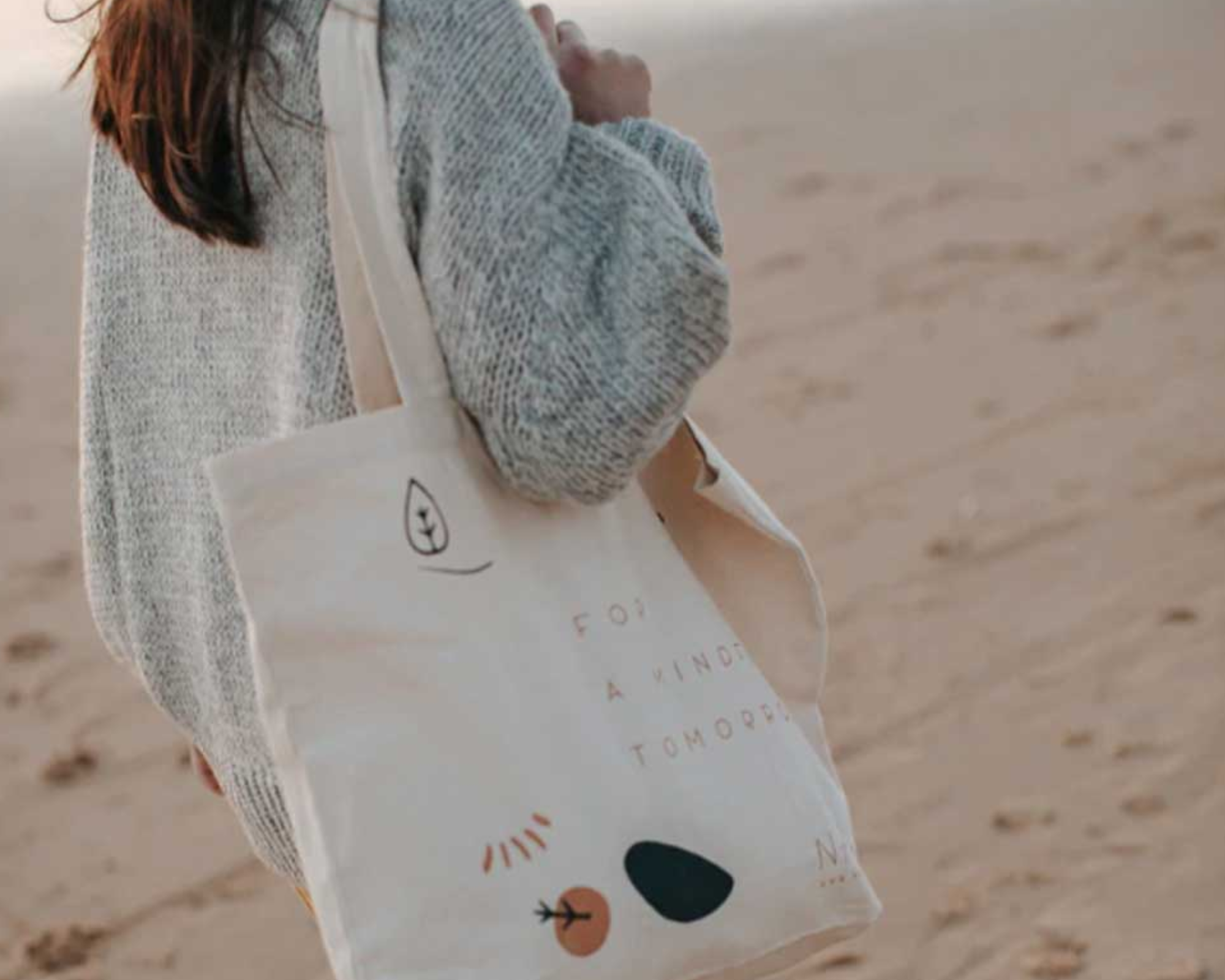 Someone walking on a beach with a more sustainable tote bag by Naz.