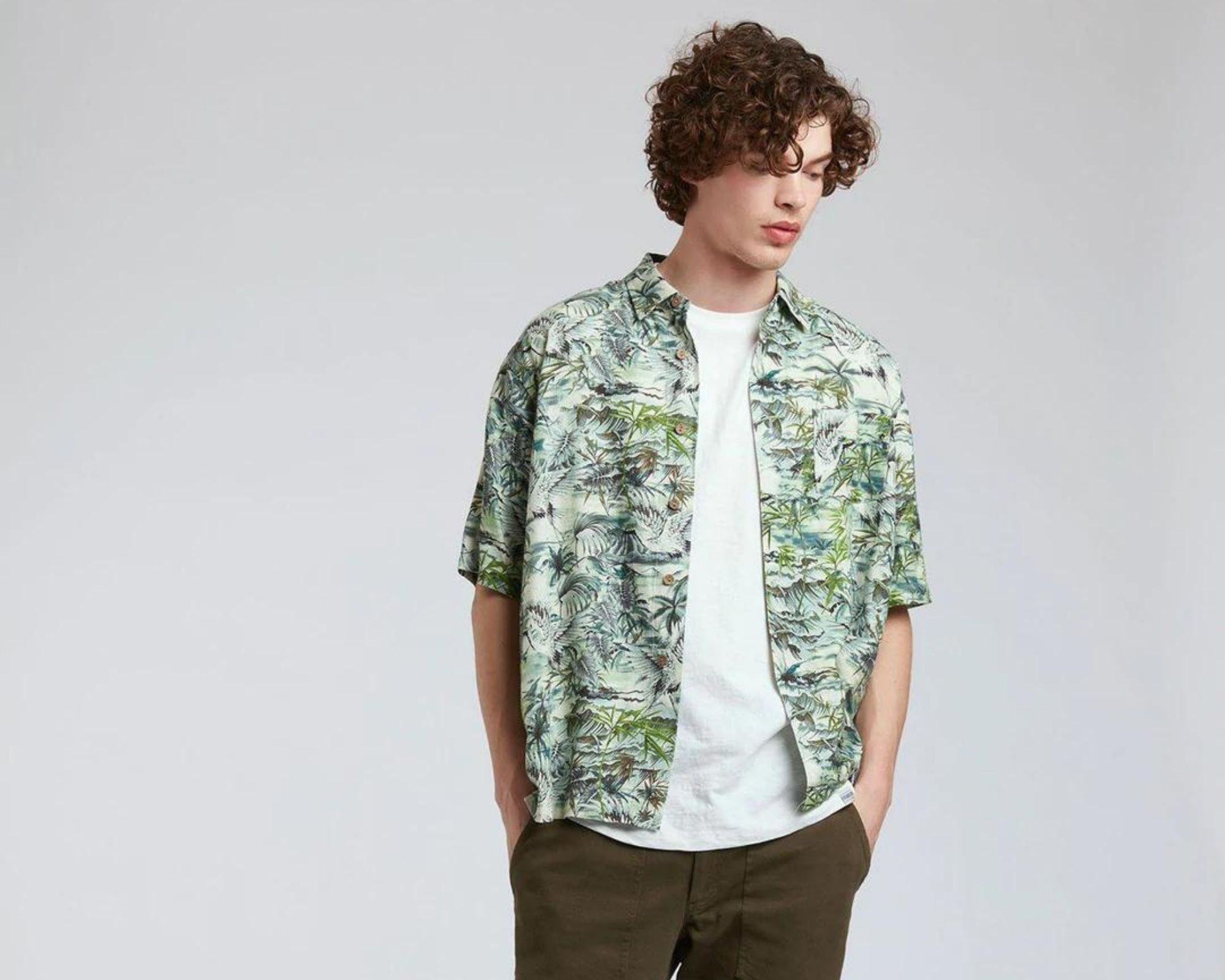 A person wearing a green plant printed button up shirt by Komodo via Staiy.
