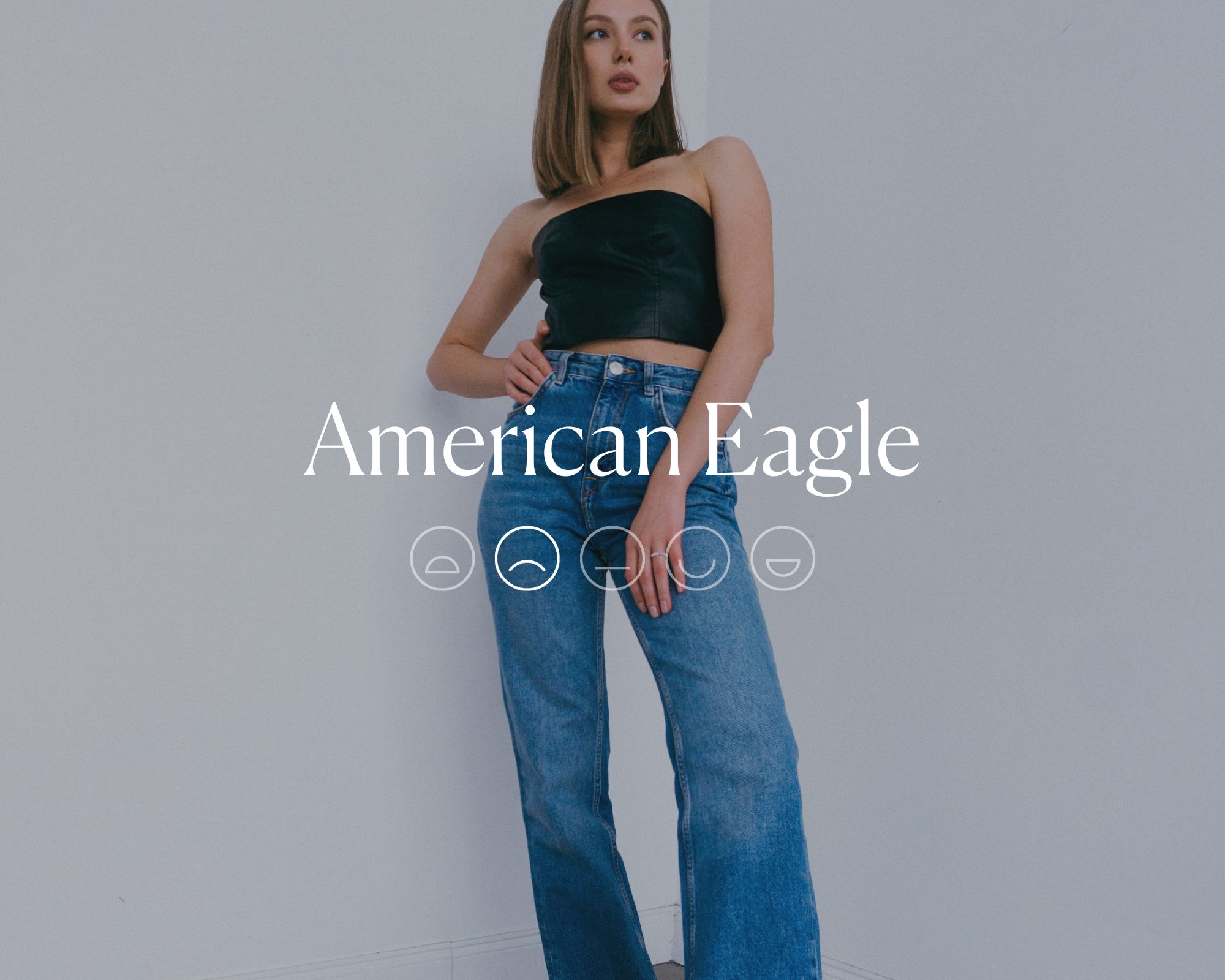 Someone wearing wide leg jeans with the words American Eagle overlaid in white text above a highlighted sad emoji face.