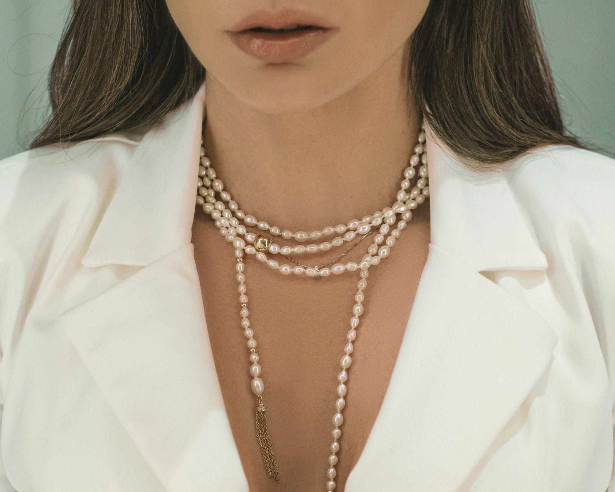 A close up of someone wearing a long pearl necklace.
