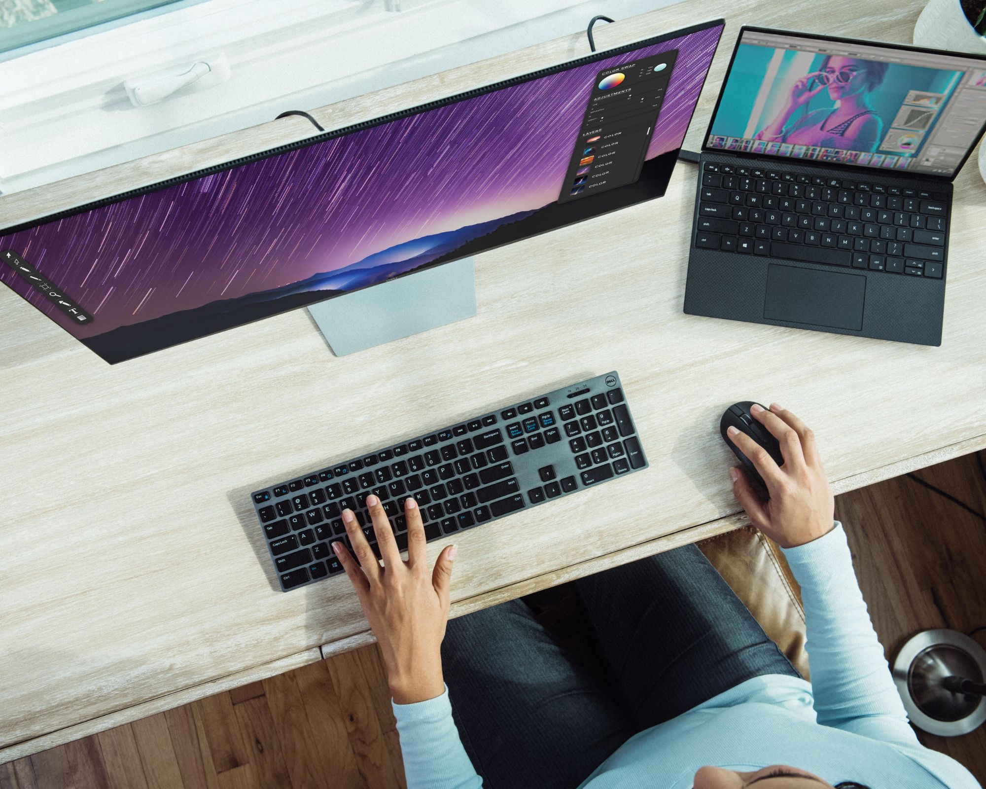 Someone using a PC and laptop with brightly coloured screens.