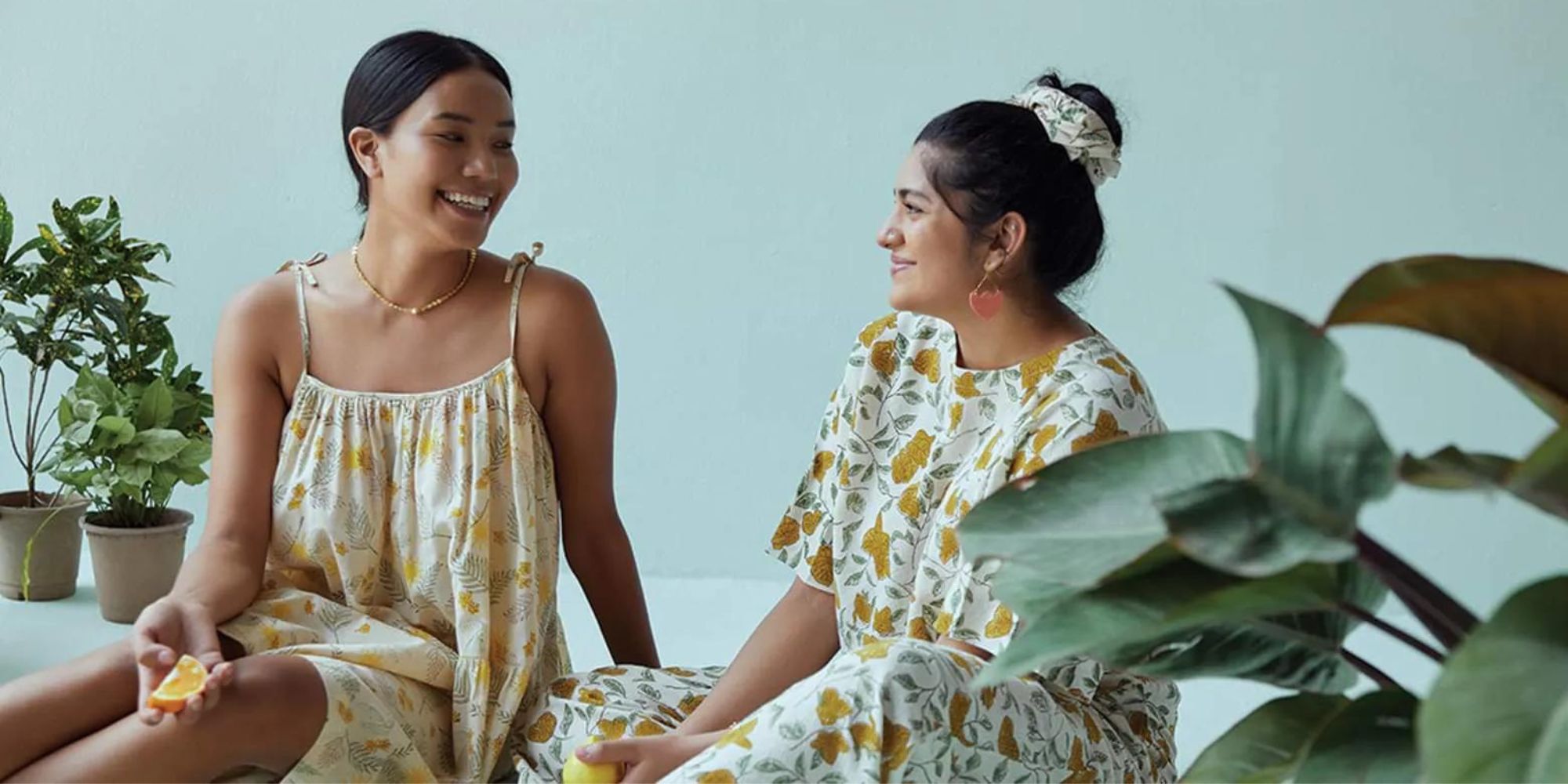 Two people wearing dresses made by Indian brand SUI.