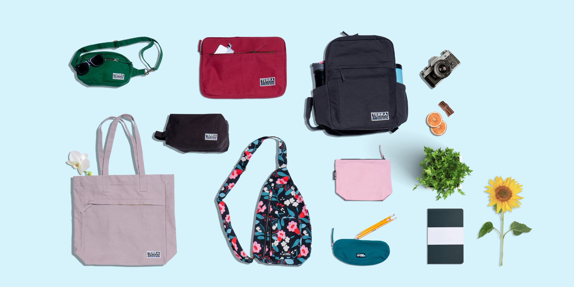 A selection of Terra Thread's organic cotton backpack and bags laid out on a blue background.