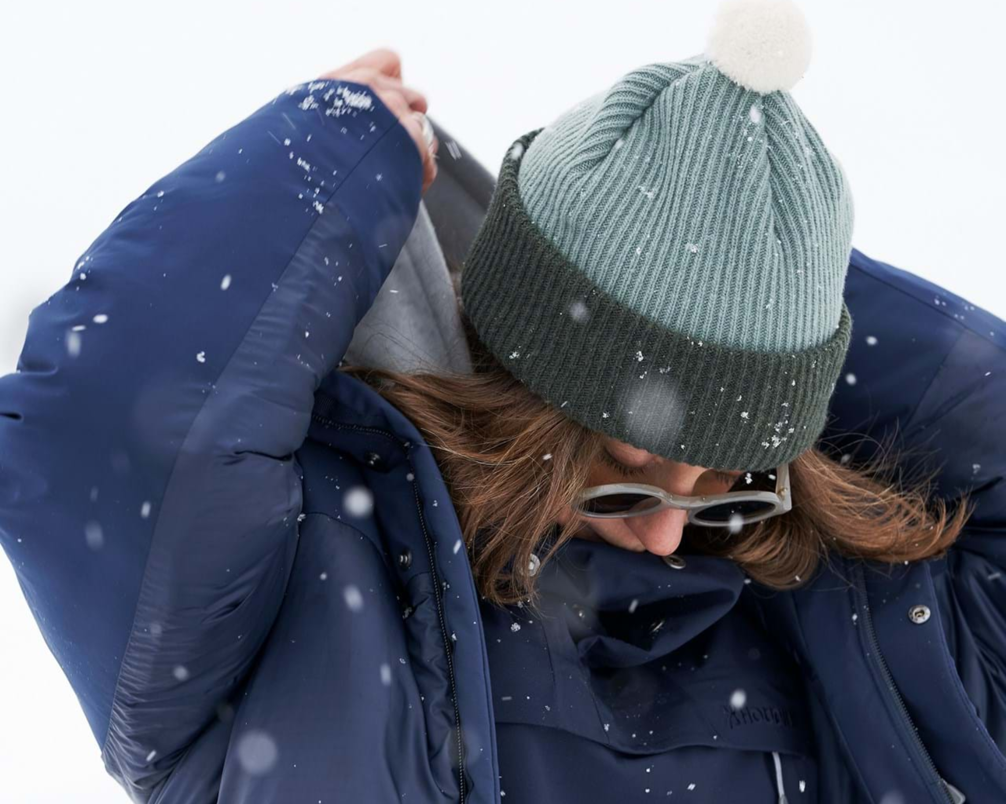 Someone in the snow raising their hood overhead wearing Bouncer jacket by Houdini.