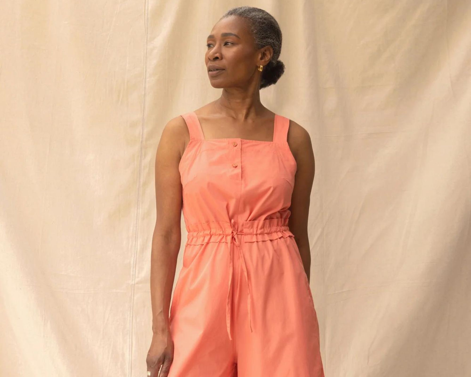 A model in a salmon-coloured wide leg responsibly-made jumpsuit by top-scoring brand ReCreate.