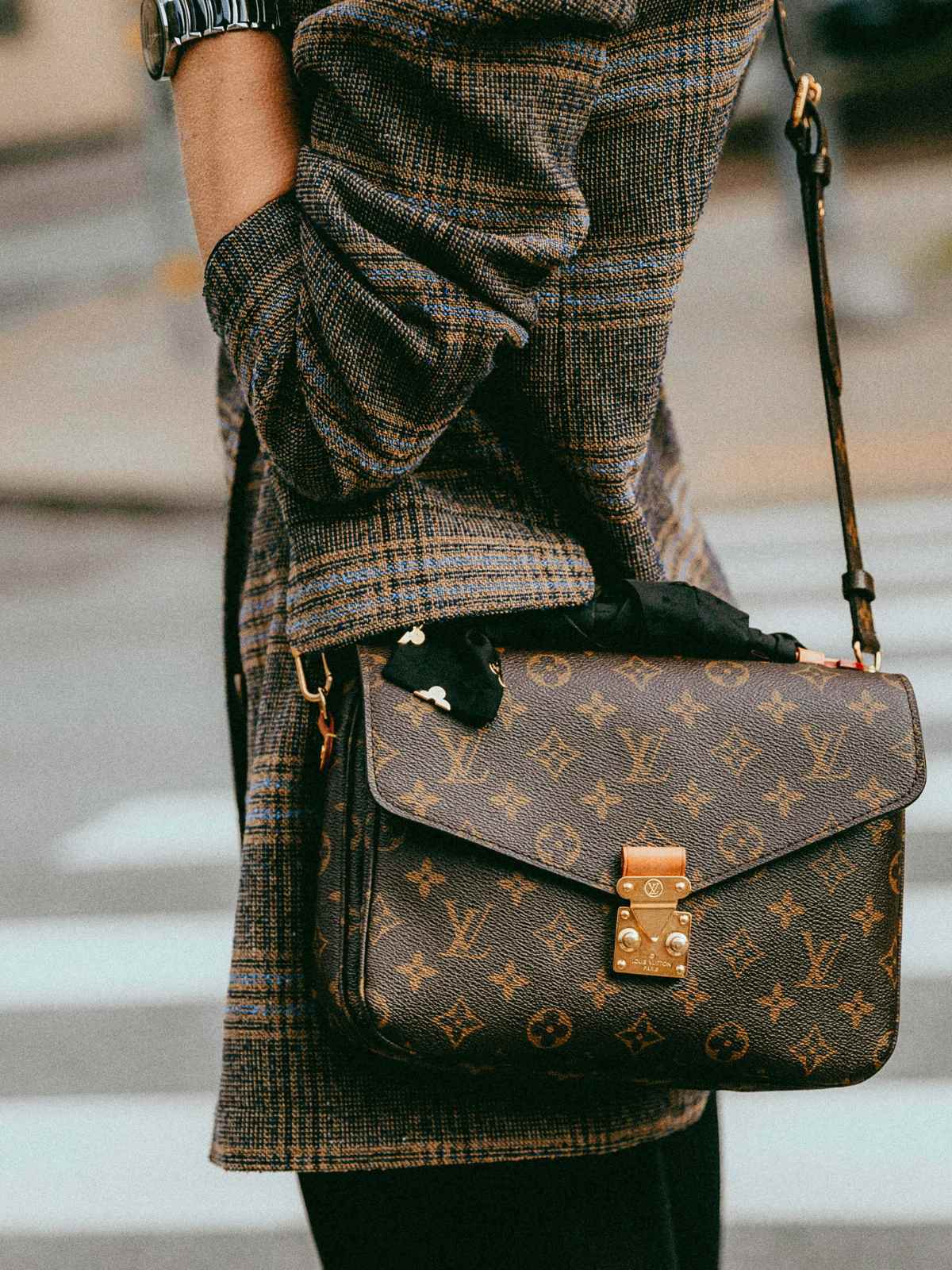 person wearing checked blazer and louis vuitton bag